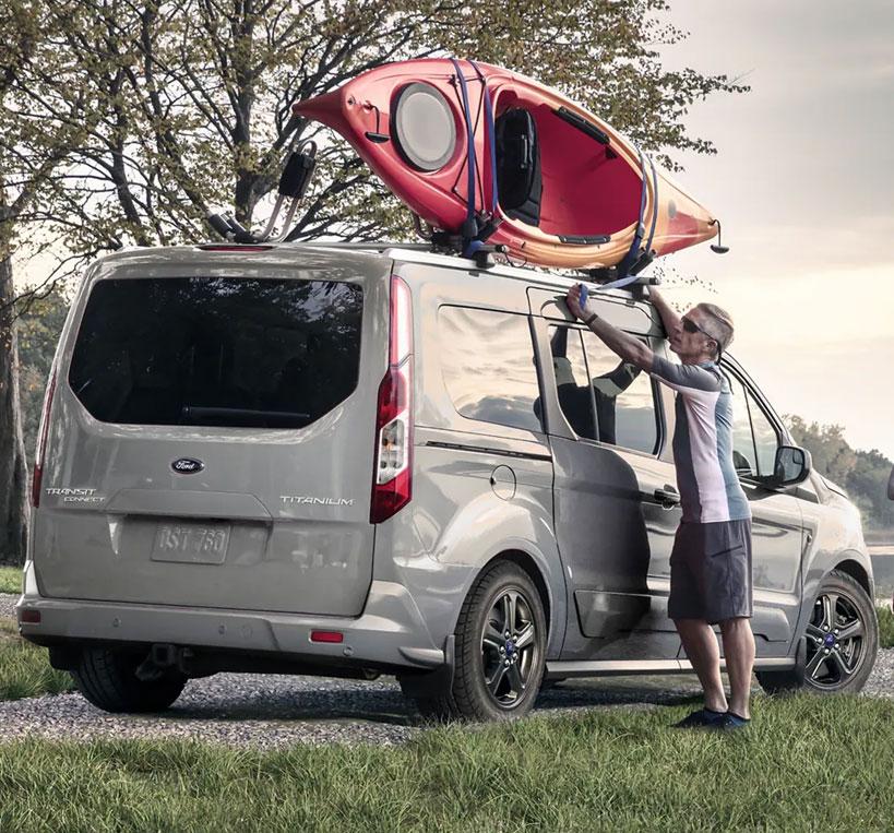 Man putting a kayak on top of his 2022 Ford Transit Connect 