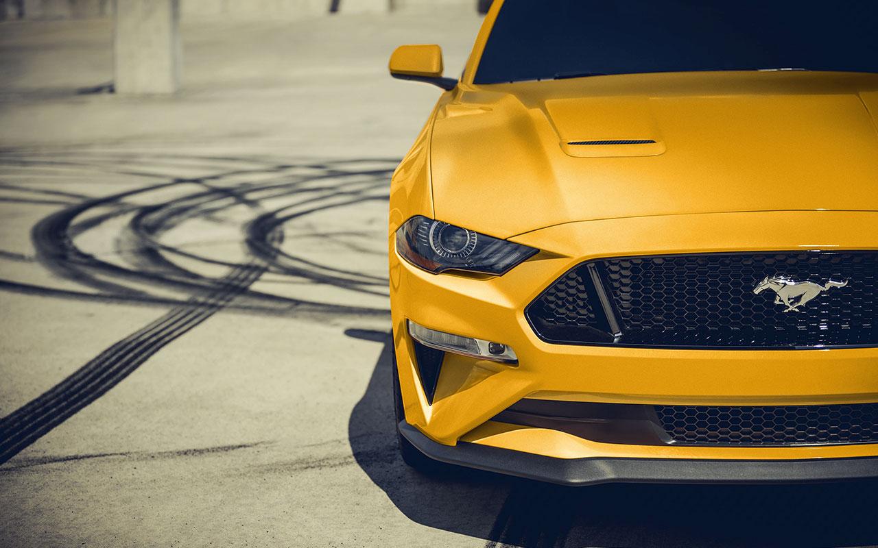 Font of a yellow 2022 Ford Mustang next to donut tire circles