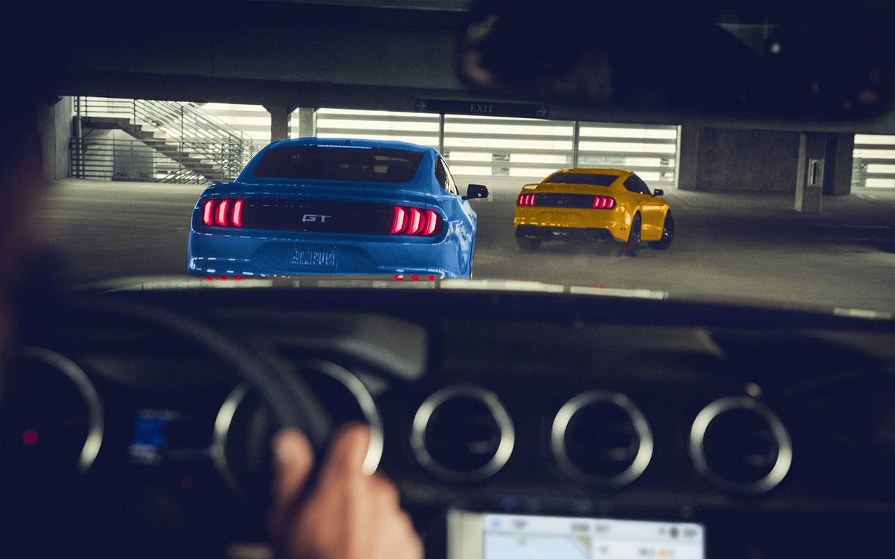 Interior driver view of a 2022 Ford Mustang looking behind two more mustangs