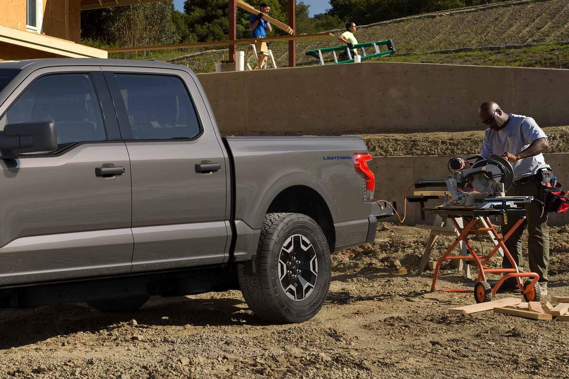 Man using a power saw connected to his 2022 Ford F-150 Lightning 