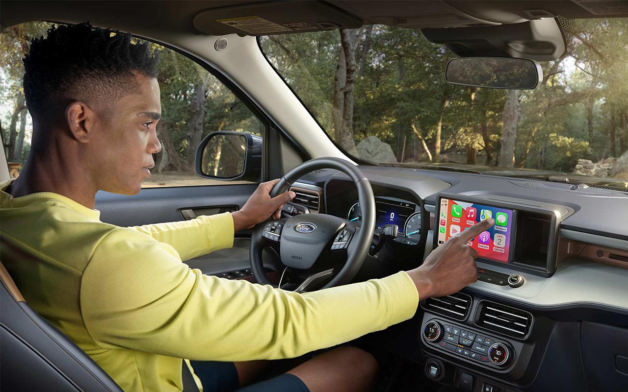 Man driving 2022 Ford F-150 Maverick while using screen features