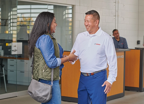 Bosch Auto Service shop manager greeting a satisfied auto repair customer
